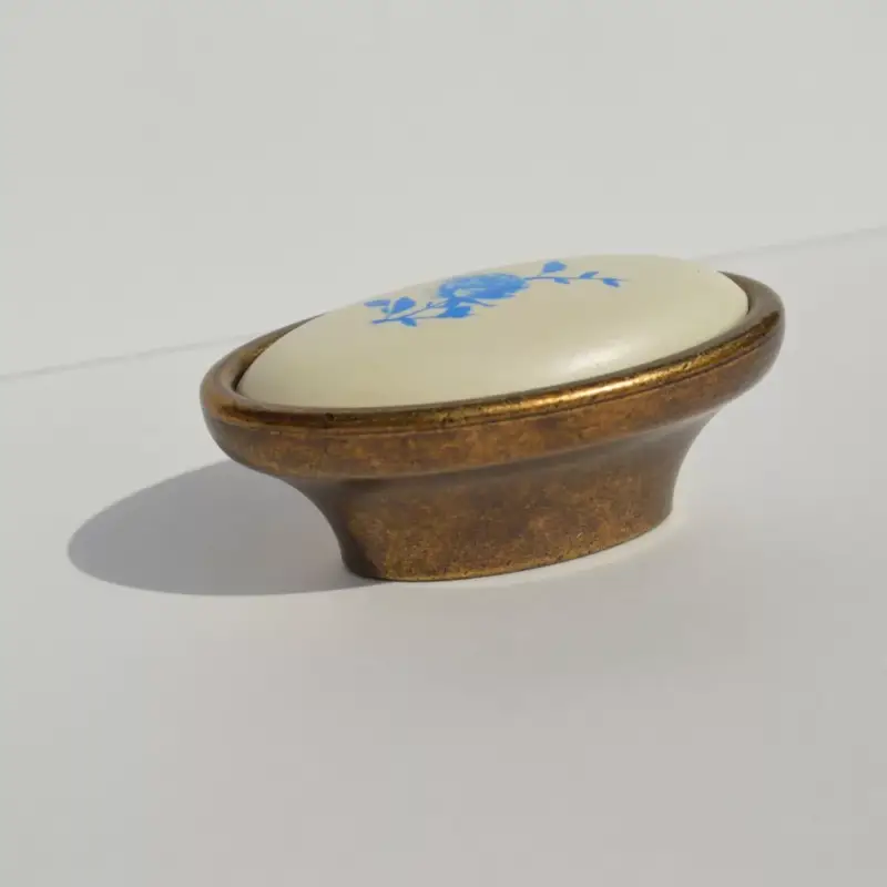 Fém-műanyag bútorfogantyú, bronz színű kék virág mintával, 16 mm furattávval Nézd meg most